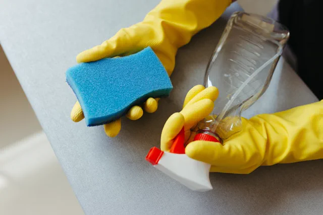Cleaning gloves, spray bottle and sponge used for deep cleaning kitchens and bathrooms